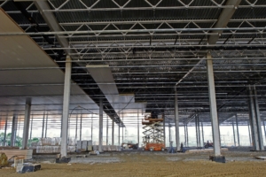 Installation of insulation panels on the ceiling of a new commercial warehouse construction site.